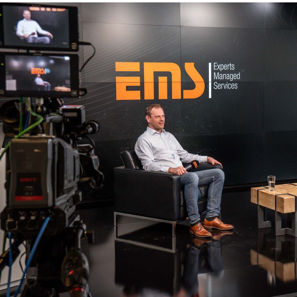 Mann sitzt im TV Studio von EMS GmbH im Filmstudio Nürnberg