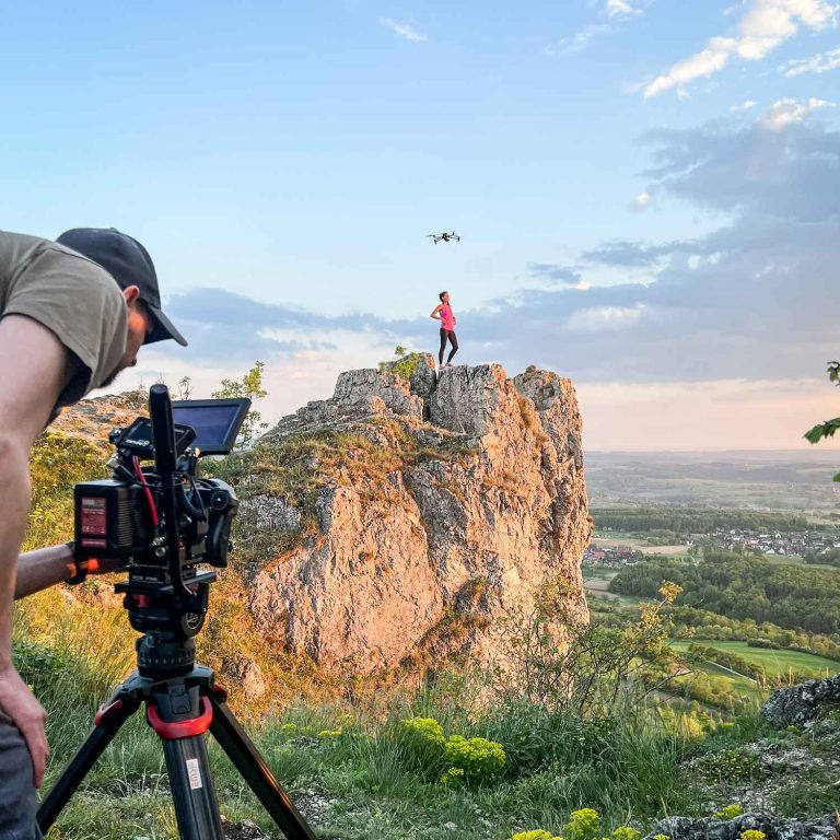 cameraman is filming a actress on a rock, drone is flying